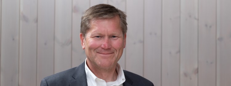 Finn Ivar Marum ny styreleder i Moelven Industrier . Mann foran panelt vegg, smiler. Foto