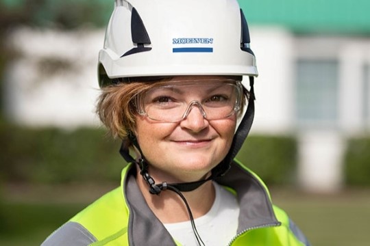 portrett av Karin Löfgren med säkerhetsutrustning, vit hjälm och gul jacka